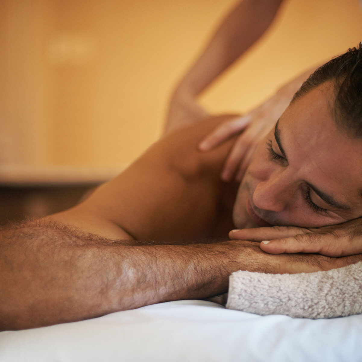 Relax, massage and man at hotel spa for health, wellness and balance with luxury holistic treatment. Self care, vacation and person on bed for muscle therapy, comfort and zen with body pamper service.